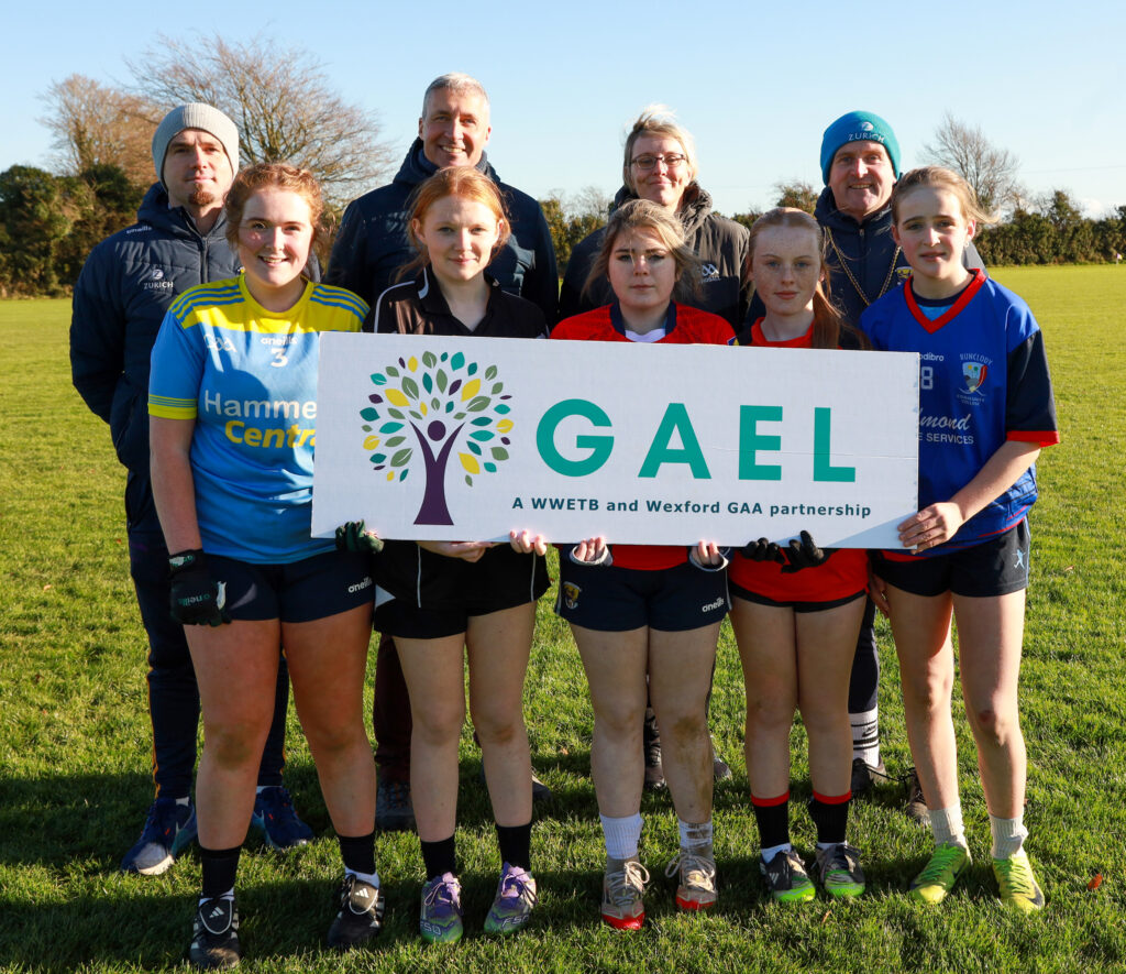 Group of adults in back row and group of teenage girls in front row holding sign - saying GAEL